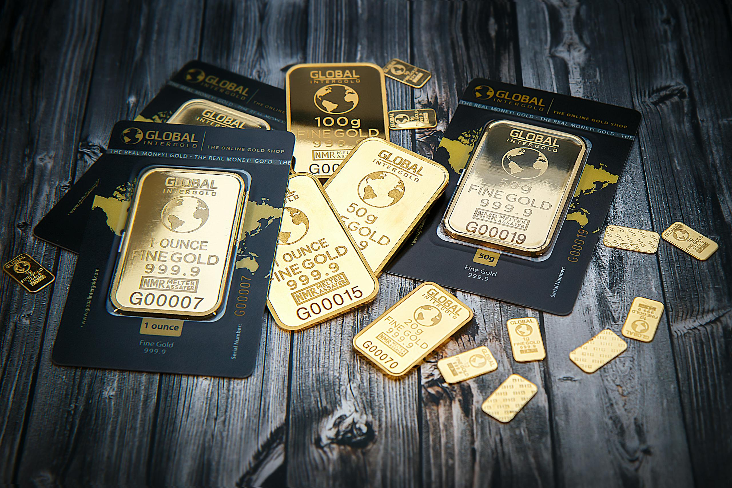 A collection of fine gold bars displayed on a textured wooden surface.